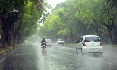 रतनपुर में मानसूनी बारिश के दौरान सड़कों पर पानी और छाता लिए चलते ग्रामीण